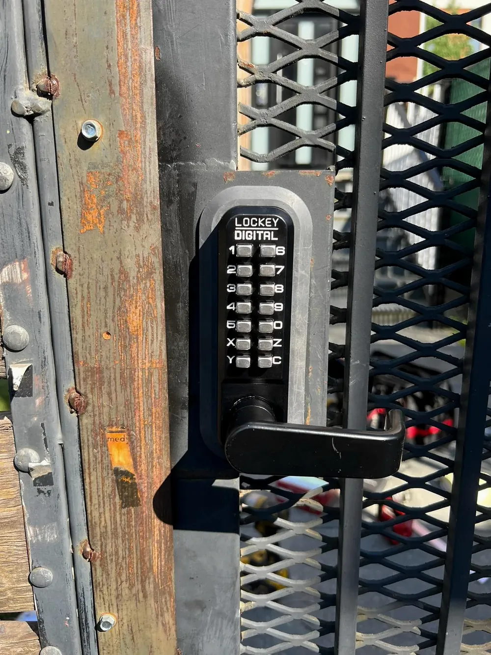 Mechanical keypad lock on a mesh security gate