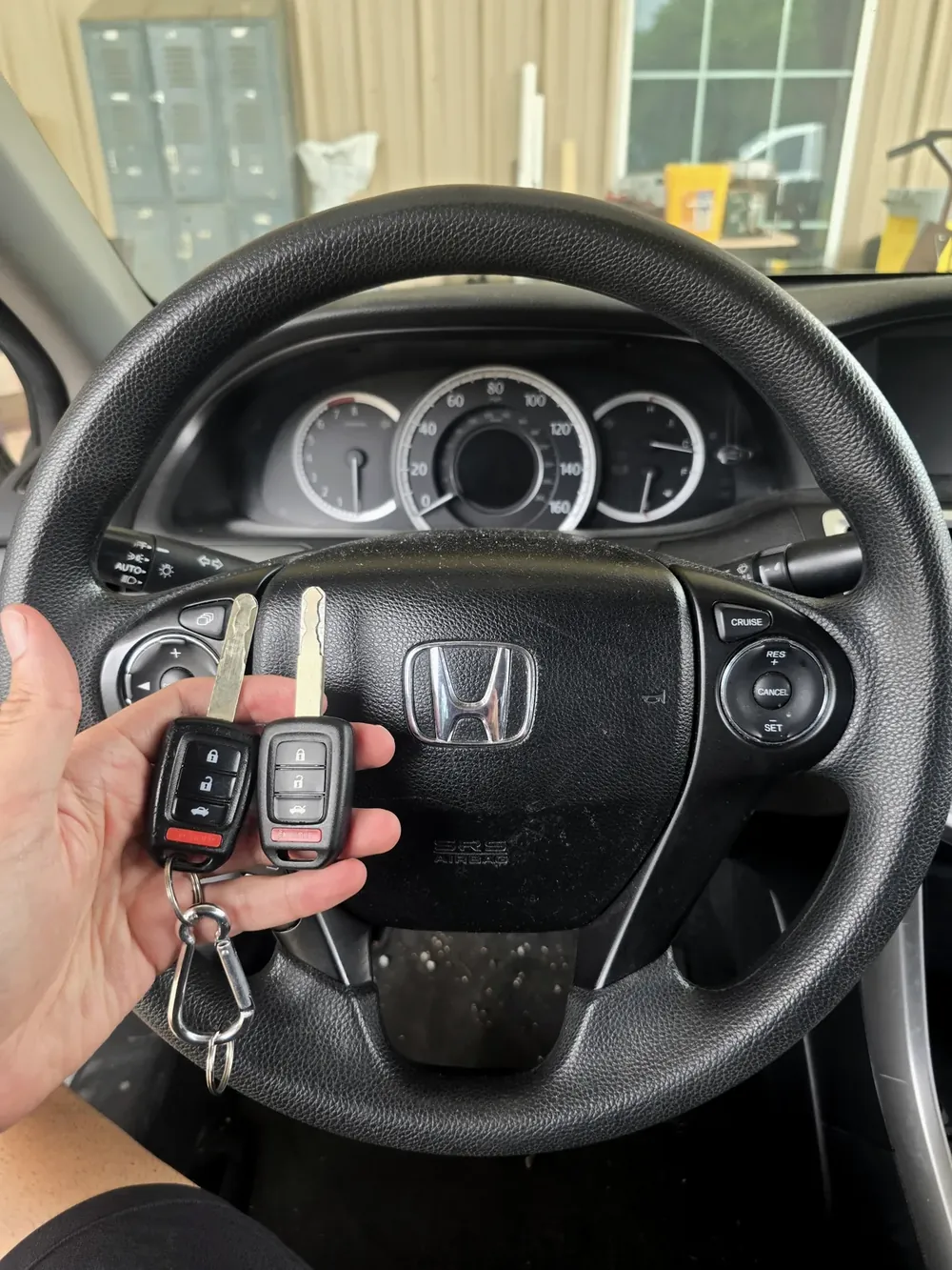 New Honda key and a spare key held at the steering wheel