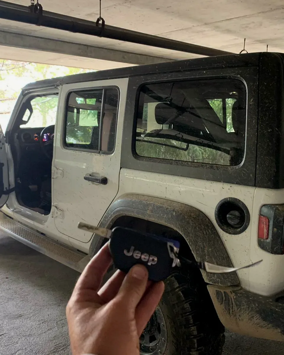 New Jeep key held next to a Jeep Wrangler in a parking garage by a locksmith serving Elmont, NY