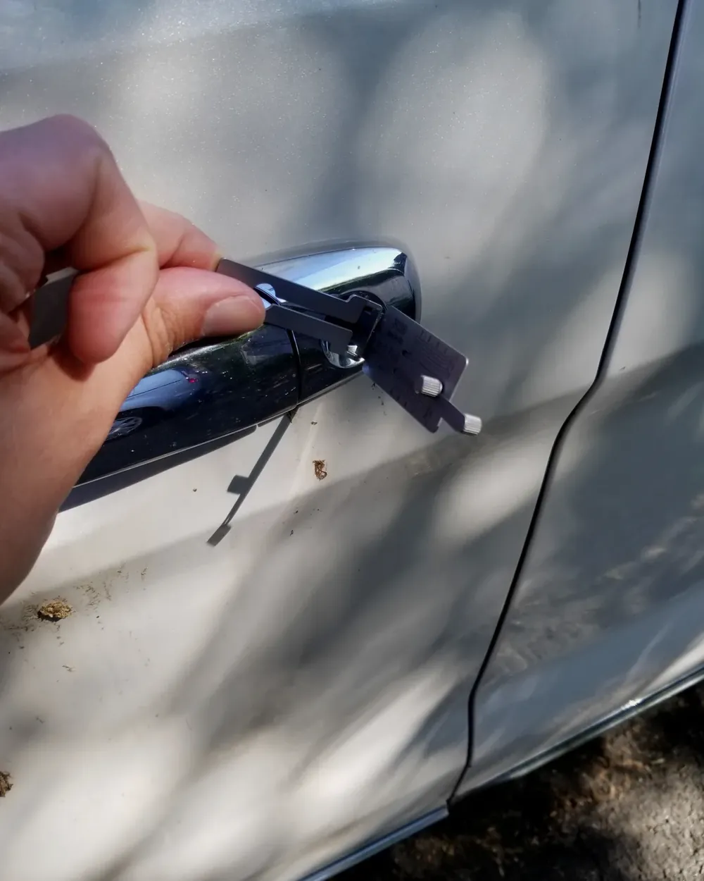 Cerrajero abriendo la cerradura de la puerta de un carro con una herramienta profesional