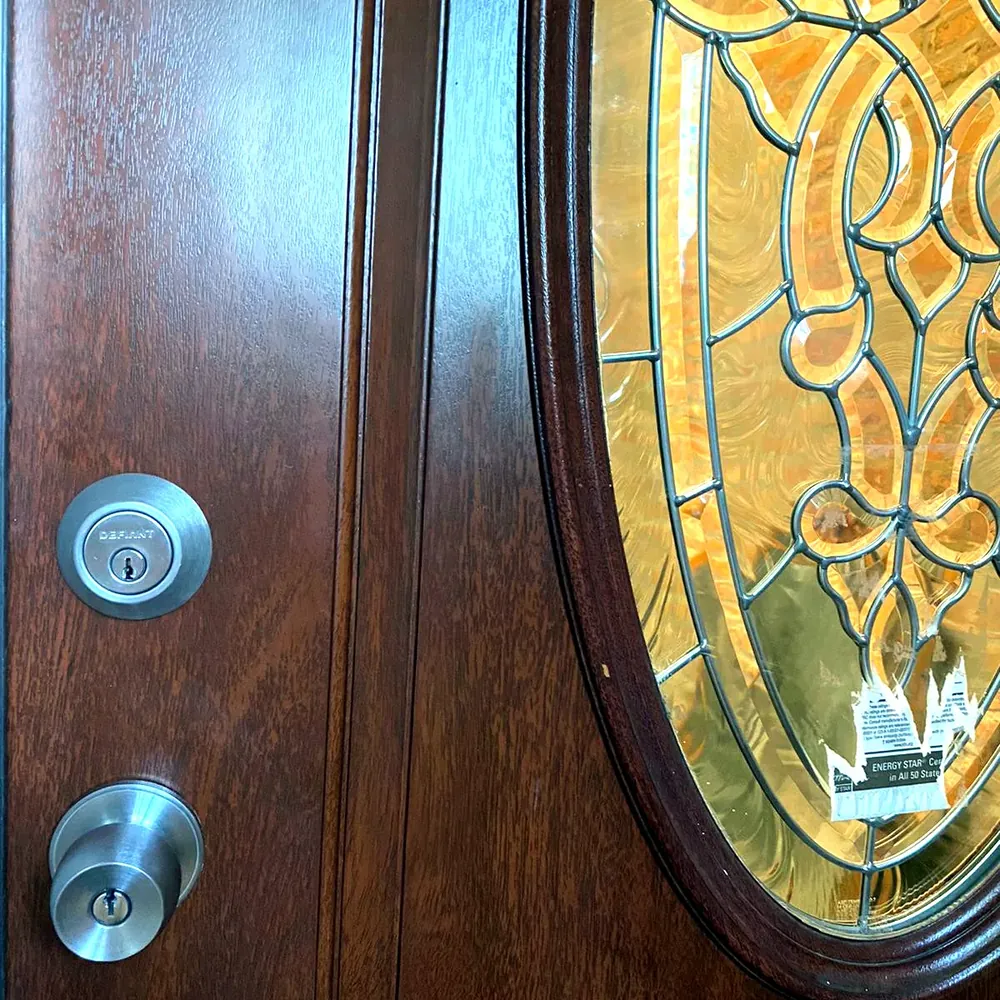 Deadbolt and knob lock on a wood front door with a leaded glass window