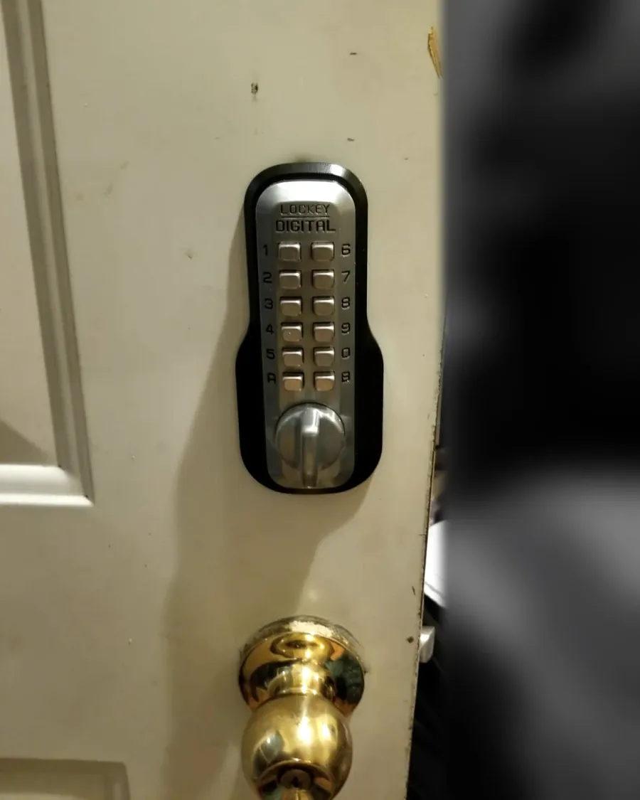 Mechanical push-button Shabbos lock installed above a door knob on a home door